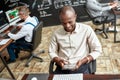 Do more, earn more. Cheerful african male trader sitting by desk and studying analytical reports using tablet pc in the