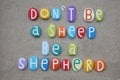 Do not be a sheep, be a shepherd, creative quote composed with multi colored stone letters over beach sand