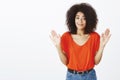 Do not blame me. Portrait of unaware beautiful african-american girl with afro haircut, smirking at camera, raising palm