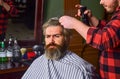 Do not cut your own hair. Hipster client getting haircut. Barber with scissors and client. Barber works on hairstyle for