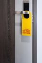 Do not disturb room label tag hotel sign hanging on modern metal doorknob handle on wooden door with workspace for your own Royalty Free Stock Photo