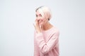 Talkative mysterious pretty beautiful woman with dyed hair dressed in pink sweater is saying secret Royalty Free Stock Photo