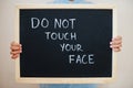 Do not touch your face. Coronavirus concept. Boy hold inscription on the board