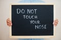 Do not touch your nose. Coronavirus concept. Boy hold inscription on the board