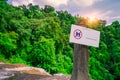 Do not walk of the trail. Warning sign in national park hang on concrete pole at waterfall in green tropical forest. Warning sign