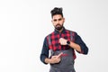 We do ontime. Young confident handyman with beard in blue overall and red t-shirt standing and showing time on his wrist watch Royalty Free Stock Photo