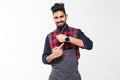 We do ontime. Young confident handyman with beard in blue overall and red t-shirt standing and showing time on his wrist watch Royalty Free Stock Photo