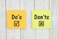 Do`s and Don`ts on two sticky notes  on weathered whitewash textured wood Royalty Free Stock Photo