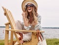 Do less, stress less. a beautiful young woman relaxing on a chair next a lake.