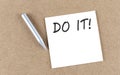 DO IT text on sticky note on a cork board with pencil Royalty Free Stock Photo