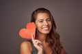 Do what makes your heart happy. Studio shot of an attractive young woman holding a blank red heart against a gray Royalty Free Stock Photo