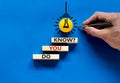 Do you know symbol. Businessman hand. Wooden blocks with words `do you know`. Beautiful blue background. Yellow light bulb icon.