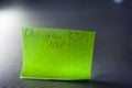 Do you love me question message written on bright green sheet writing paper note with heart on blue background