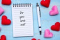 DO YOU LOVE ME? word on note book and pen with red and pink heart shape decoration on blue wooden table background. Love, Wedding Royalty Free Stock Photo