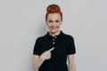 Young cheerful caucasian red haired woman pointing at herself while standing isolated over grey wall Royalty Free Stock Photo