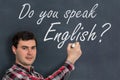 Do you speak English? Man with chalk writing on blackboard Royalty Free Stock Photo