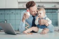 Pleasant caring father smiling and holding a bottle.