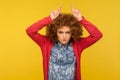 Do you want problems? Portrait of angry curly-haired woman showing bull horn gesture and threatening to attack Royalty Free Stock Photo