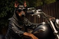 A Doberman dog in a leather jacket and black glasses sits on a bike and looks at the camera Royalty Free Stock Photo
