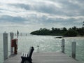 Dock with a bench overlooking water on a cloudy day. Old fashion gas pum on the dock.