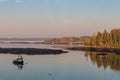 Dock and boats in bay in Boothbay, Maine, at sunrise in summer in soft beautiful light on reflective water