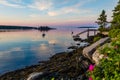 Dock and boats in bay in Boothbay, Maine, at sunrise in summer in soft beautiful light on reflective water