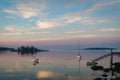 Dock and boats in bay in Boothbay, Maine, at sunrise in summer in soft beautiful light on reflective water