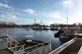 Dock with Boats on a River, under a Blue Cloudy Sky, on a Winter Morning, with Industry Buildings