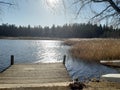 Dock on a lake. Peacful sunny day.  Calm lake and sun. Wind blowes on the sunny lake. Forest and lake. Alone. Calmness. Royalty Free Stock Photo