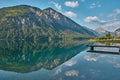Dock leading into a reflecting mountain lake in the Austrian alps Royalty Free Stock Photo