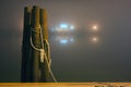 Dock pilings wrapped in rope in the foggy mist