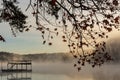 A dock surrounded by fog and framed by leaves on a winter morning at sunrise on Lake Lanier outside of Atlanta, Georgia, USA Royalty Free Stock Photo