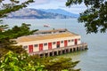 Dock warehouse with boat out on San Francisco Bay waters framed in by green leaves of trees Royalty Free Stock Photo