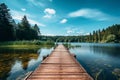 A dock with wooden path on a lake with green forest landscape. Beautiful summer nature background, calm blue water in the river Royalty Free Stock Photo