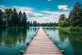 A dock with wooden path on a lake with green forest landscape. Beautiful summer nature background, calm blue water in the river Royalty Free Stock Photo