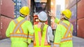 Dock workers in safety gear stand in front of massive containers Royalty Free Stock Photo