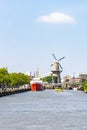 A docked cargo ship, water taxis and in the background the Wind corn mill `De Distilleerketel` in Delfshaven