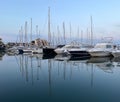 docked sailboats and their reflection in the calm water of the marina