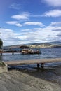 Docks and boat on lake shore with beach. Mountains and sky over lake. Royalty Free Stock Photo