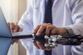 Male doctor in white coat, hand using wireless mouse and work on laptop computer Royalty Free Stock Photo