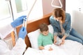 Doctor adjusting intravenous drip for little child in hospital during parent`s