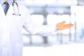 Doctor advertising your product. doctor pointing away while standing against grey background. Royalty Free Stock Photo