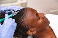 Doctor aesthetician makes head beauty injections to a female african patient Royalty Free Stock Photo