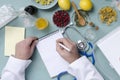 Top view of doctor`s workplace. Doctor of traditional medicine writing down the prescription for patient.Natural medicines, dry be