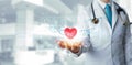 Doctor analyzing holding red heart shape in hand with modern virtual screen interface. Healthcare and medicine concept Royalty Free Stock Photo