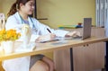 Doctor asian woman sitting and working on desk using labtop and writing note at hospital,Happy and smiling Royalty Free Stock Photo