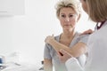 Doctor assisting mature patient in stretching her arm at hospital Royalty Free Stock Photo