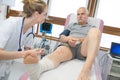 Doctor bandaging leg patient in hospital