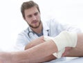 Doctor bandaging a wound on the leg of the patient