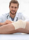 Doctor bandaging a wound on the leg of the patient